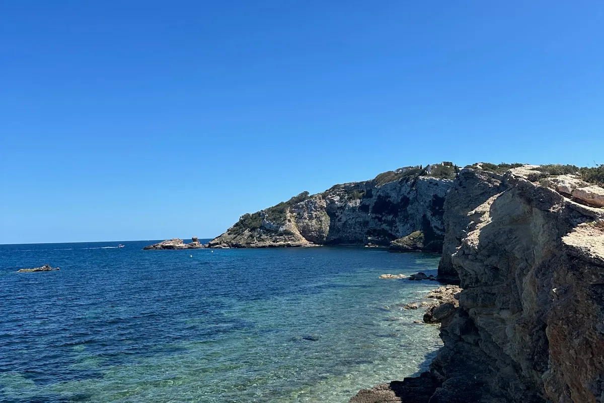 Rocky cliff formations and natural pools at the coast, with deep blue water