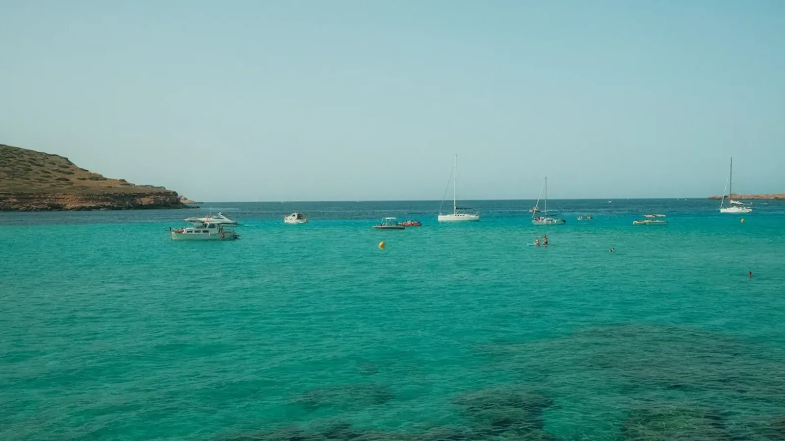 Boat anchored in a calm turquoise Ibiza cove
