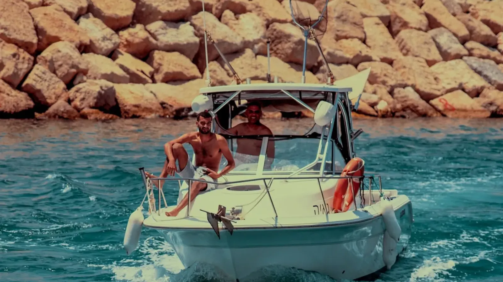 Friends playing in the turquoise water beside a charter boat in Ibiza